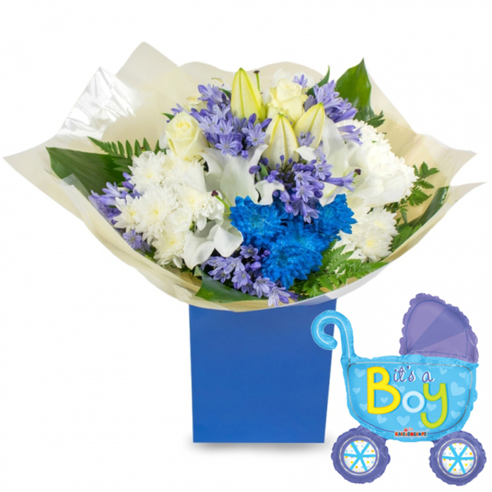 An uplifting newborn gift: a carefully layered bouquet in a sturdy royal-blue rectangular presentation box, styled to celebrate a baby boy with classic whites and bold blues. The arrangement places creamy white roses at its center, ringed by voluminous white chrysanthemums and a scattering of lilies with several buds waiting to unfurl, lending a feeling of anticipation. Bright electric-blue chrysanthemums form a lively cluster that commands the eye, while soft lavender-periwinkle clusters-resembling hyacinth or similar bell-shaped florets-trail through the stems and add delicate texture and gentle scent. Fresh green leaves and fern fronds provide structural contrast and a natural, garden-fresh aroma. The base is wrapped in slightly crinkled, translucent cream paper that tucks neatly into the box, adding a tactile layer of refinement against the matte blue surface. A glossy light-blue foil balloon shaped like a pram floats to the right of the box; darker blue detailing on the canopy and wheels, tiny polka dots and heart shapes, and the playful It's a Boy script in vivid yellow and lime-green announce the joyful occasion with cheer. The composition sits in soft, diffused light that accentuates petal textures and the balloon's metallic sheen, evoking the hush and happiness of a maternity ward or a sleepy nursery. This thoughtful pairing-floral elegance with a whimsical balloon-is perfect for celebrating a newborn in Stanmore, whether delivered to a hospital room at the Royal National Orthopaedic Hospital, left on a doorstep on Stanmore Broadway, or presented at a local baby shower near Canons Park.