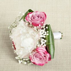 Handcrafted by a passionate Stanmore florist, this bridal or bridesmaid bouquet radiates with heartfelt artistry and local charm. At its core, a lush white peony blooms in fullest splendour, layers of petals billowing like soft clouds, exuding grace and quiet opulence. Two signature pink roses flank the arrangement-one situated near the top left, the other anchored at the bottom right-each showing a delicate gradient from bold, magenta outer petals to a subtle, lavender-tinged blush at the centres. Their spiral forms suggest new beginnings, reminiscent of Stanmore's own awakening gardens each spring. Wispy sprays of enchanting baby's breath weave between the principal blooms, their tiny, starlike white flowers lending airy texture and a touch of enchantment. Framing the bouquet, broad emerald leaves-deep green and satin-smooth-create a vibrant, modern collar, while a crisp white ribbon holds the stems in a polished, inviting handle, perfect for elegant celebrations in and around Stanmore. Set atop a neutral, textured fabric background, the bouquet is lit with gentle, even light, which draws out the intricate petal and leaf details. This arrangement is perfect for weddings, anniversaries, or heartfelt moments where sophistication and beauty are cherished, much like the quiet corners and historic landscapes found throughout Stanmore.