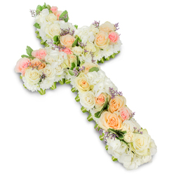 A beautifully arranged floral cross stands out crisply against an immaculate white background, giving the overall composition a sense of reverence and calm. The cross is lush and full, covered completely with fresh flowers so that no support structure can be seen, just a continuous blanket of petals. White and creamy ivory blooms form the dominant base, with large, cushiony clusters that suggest hydrangeas, interwoven with tightly packed white roses and other small, rounded flowers. Nestled amidst this white expanse, pastel roses provide gentle notes of colour-soft blush pink, muted peach, and light apricot tones that drift along the vertical and horizontal arms like a tender whisper of warmth. Here and there, slender stalks of lavender or pale purple filler flowers rise slightly above the main surface, adding delicate texture and a subtle, spiritual feel. Small touches of green foliage are visible mainly at the edges, giving the cross a lightly framed outline that enhances its silhouette without breaking its softness. The lighting is bright but diffused, mirroring the clear daylight one might experience walking through Stanmore's quiet residential streets on the way to a church service. This floral cross feels like a heartfelt tribute created by caring hands, ideal for a funeral or memorial held in one of Stanmore's local chapels, where family and friends gather to share memories. It carries a quiet message of peace, hope, and remembrance, offering a gentle focal point of beauty during a time of loss.