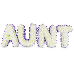 As a florist who works in and around Stanmore, I describe this design as a personal, reverent statement: the word AUNT sculpted in bold capital letters, each letter densely composed of hundreds of small, pristine white spray chrysanthemums. The chrysanthemums create a plush, cloudlike texture across each letter's surface, their tiny petals overlapping like silk; here and there the pale yellow centres of individual florets add a whisper of warmth, keeping the white from feeling stark. Around the perimeter of every letter runs a deep purple satin ribbon, ruffled and pleated to give a soft, scalloped edge that both frames and elevates the flowers; the ribbon's satin catch subtly reflects chapel lights or the diffuse daylight of an overcast Stanmore afternoon. Grey shadows beneath the letters reveal their dimensional frames and separate them gently from the white backdrop, making the tribute read clearly from a distance at a service. There is a quiet vegetal scent, clean and green, and an overall impression of calm, respect and love. This is the sort of bespoke memorial piece we prepare with care at Flowers Stanmore for families who want a named tribute that is both traditional and quietly uplifting - suitable for display at funerals near Stanmore High Street, in small community memorials or placed with other floral tributes at home viewings. The arrangement's balance of texture, colour and form offers solace, a handcrafted emblem of remembrance.