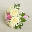 A finely arranged bouquet rests on creamy woven linen reminiscent of Stanmore's stylish event decor, embodying classic romance with a modern touch. The main feature is a cluster of five creamy white or pale yellow roses in full, lush bloom, their velvety petals softly open as if basking in gentle morning light. Just off-center sits a striking magenta-pink rose, providing both a bold highlight and a sense of individuality-a flourish well suited to the sophisticated gatherings in Stanmore Park. Sprigs of delicate baby's breath add a whisper of airy texture throughout, elevated by the presence of deep green leaves that tuck naturally around the flowers. The bouquet's neatly bound stems are dressed in textured, bright pink ribbon, mirroring the celebratory energy of local weddings. Subtle spirals of tiny, iridescent pearls trail around the handle, casting a touch of luxury for occasions where elegance and joy go hand in hand. With every detail captured in soft light, this arrangement reflects the high standards of Stanmore's talented florists and suits any occasion-from intimate nuptials to vibrant anniversary celebrations-where classic style and heartfelt sentiment shine.