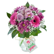 Vivid and inviting, this bouquet is a celebratory display of purple and pink blooms arranged with the precise eye of a Stanmore florist. Pale lavender roses anchor the heart, their soft petals drawing in the gentle scent of early spring mornings on Stanmore's leafy streets. They are embraced by brilliant fuchsia Gerbera daisies, whose open, smiling faces and deep centers reflect the joyful spirit cascading from Stanmore's local community flower beds. Adding drama, tightly packed magenta chrysanthemums dot the arrangement, their texture and colour providing both depth and a touch of mystery. Ethereal sprigs of baby's breath are woven among the larger blooms, infusing a frothy airiness throughout. Rich green leaves peek between the flowers, cradling the bouquet in natural splendour. All of this is carefully set in a clear, rounded glass vase with a distinctive crackled finish, catching glimmers of light like early dew on Stanmore Common. A rustic strand of raffia ties around the neck of the vase, suspending a crisp, blank tag awaiting your message. This bouquet delivers delight with every detail-ideal for sharing love, joy, or appreciation, whether for a birthday or simply to brighten a home in Stanmore with locally arranged freshness.