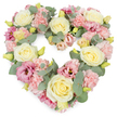 A serene heart-shaped floral tribute dominates the frame, artfully styled against a clean white background that lets its pastel tones speak clearly, as if waiting to be delivered to a service in Stanmore. The heart is lush and complete, its outline defined by the dense placement of flowers and foliage, leaving no gaps or exposed base. Soft cream and pale yellow roses sit like gentle beacons throughout the design, their rounded, layered petals unfolding gracefully. Between them, light pink carnations are closely packed, their ruffled edges overlapping in soft waves that lend the wreath a comforting, almost pillow-like surface. Deeper magenta-pink and mauve lisianthus blooms are scattered among the pastels, their more open, slightly curled petals and occasional darker centres providing depth and subtle contrast, much like small highlights of memory amid the gentler shades of grief. Sprigs of silvery-green eucalyptus wind through the arrangement, their rounded leaves and cool matte colour outlining the heart and adding a sense of calm, natural movement. Tiny yellow-green buds dot the design here and there, suggesting freshness and the fleeting promise of new life. The lighting is even and soft, allowing every texture and colour to be appreciated without distraction. This kind of heart-shaped wreath is often chosen as a touching funeral or sympathy tribute in Stanmore, conveying love, respect, and remembrance in a quiet yet deeply felt way. It offers a tender visual expression of support for families and friends gathering to say goodbye, blending traditional beauty with gentle, contemporary pastel tones. 