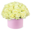 A chic, round hat box in soft pastel pink cradles a lush dome of roses, each bloom a delicate shade of cream or pale ivory with the faintest suggestion of pastel yellow at its centre. The roses are arranged so tightly that they form a perfect, overflowing hemisphere, with every velvety petal brushing up against the next, giving the impression of a single, abundant cushion of flowers. The blossoms are fully open or nearly at their peak, their layered spirals creating depth and movement across the surface of the dome, much like the gentle undulation of the greenery around Stanmore Country Park. Small touches of fresh green foliage appear at the base, only just visible between the dense rose heads, adding a whisper of contrast that enhances the creamy tones without disrupting the arrangement's calm refinement. The hat box's matte finish gives it a sophisticated, modern feel, reminiscent of stylish gift packaging chosen with care for a milestone celebration or romantic anniversary dinner in Stanmore. Its blush-pink hue pairs harmoniously with the soft shades of the roses, creating a balanced, feminine palette. The entire scene is set against a clean white background, allowing the eye to linger on the petals' curves, the interplay of light and shadow, and the subtle variations in colour. This image conveys a sense of thoughtful generosity and quiet luxury, making it especially fitting for depicting premium floral gifts, romantic gestures, or elegant home centrepieces enjoyed by residents and couples throughout the Stanmore community.