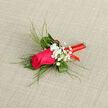 At the centre of this carefully composed boutonnière is a striking magenta rose, its petals layered in precise, velvety folds that draw the eye inwards like a finely painted detail. The rose is surrounded by a collar of lush green foliage, including smooth, deep green leaves and slender, reed-like strands that arch gently away from the bloom, adding height and a sense of airy elegance. Nestled amidst this greenery are dainty clusters of baby's breath, each tiny white flower contributing to a soft, misty texture that lends an air of classic romance often seen in traditional weddings around Stanmore's churches and local venues. The stem of the arrangement is neatly and firmly bound in a vivid red ribbon, its sheen catching the light as it coils in tidy, parallel bands from the base of the bloom down to the tip. This ribbon, with its strong, celebratory colour, provides a visually striking contrast against the pink of the rose and the fresh greens, while also suggesting care and craftsmanship. The boutonnière is photographed against a subtle, neutral fabric background, allowing the colours to stand out crisply without distraction. You can imagine this small floral accent pinned to the lapel of a well-cut jacket, perhaps for a Stanmore wedding, prom, or anniversary celebration, the rose's light fragrance accompanying the wearer as they greet guests and smile for photos. In the hands of a skilled local florist from Flowers Stanmore, each petal, stem, and twist of ribbon has been placed with intention, resulting in a wearable arrangement that feels intimate, joyful, and perfectly suited to mark a cherished occasion.