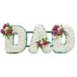 A tender, three-dimensional funeral tribute spells out DAD in bold capital letters, each character formed from a dense, cloud-like carpet of pristine white chrysanthemum florets that read as soft, cushiony texture even from a small distance. The edges of every letter are crisply framed with an emerald-green pleated ribbon, its ruffled sheen creating a cool, calm contrast to the warm white blooms. Behind the lettering a subtle dark green support bar ties the trio together, suggesting a freestanding memorial designed for display at a wake, chapel or graveside. Delicate clusters punctuate the composition: the first D carries a spray of deep magenta roses with unopened buds and small white freesia tucked into its upper left curve; the A cradles a similar bouquet in the lower central V; the final D is balanced by a matching cluster on its upper right sweep. Lush, glossy foliage nestles these accents into the white field, adding depth, weight and a shadowed green that grounds the arrangement. The scent would be quietly floral - the honeyed lift of freesia and the warm, velvety note of roses - while the visual impression is one of peaceful dignity and affectionate farewell. Lit as if by soft, neutral studio light against a pure white background, the letters read clearly and serenely, a bespoke sympathy gesture that conveys personal remembrance and honour. As a Stanmore-made tribute, this design reflects traditional funeral craftsmanship with discreet contemporary lines, suitable for families arranging services near Stanmore High Street, Canons Park or local chapels seeking a heartfelt, readable memorial display.