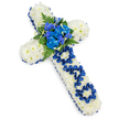 In this serene funeral arrangement, a large cross composed entirely of flowers is photographed against a bright white background, giving the tribute a sense of stillness and purity. The surface of the cross is completely filled with fresh white spray chrysanthemums, their rounded, button-like heads tightly packed so there is no empty space, creating a smooth yet softly textured foundation. Around the outer edge of every arm and along the vertical axis, a royal blue satin ribbon has been carefully applied, its refined sheen catching the light and outlining the traditional shape with clarity and grace. At the heart of the cross, where the horizontal and vertical sections meet, a prominent spray of royal blue flowers draws the eye: lush, frilled carnations surrounded by smaller, vivid blue florets that bring to mind delphiniums or dainty orchids. Dark green fern fronds curl around this central cluster, supported by sturdy leaves that introduce natural depth and a refreshing contrast to the blue and white. On the vertical stem of the cross, the word DAD appears in bold ribbon lettering, each character formed from loops and folds of the same royal blue satin, carefully tucked into the bed of chrysanthemums so the inscription feels integral to the design. Subtle shadows beneath the cross hint at its size and craftsmanship without disturbing the overall purity of the scene. It is easy to imagine this piece on display at a memorial service or graveside in Stanmore, perhaps carried from a local florist to a church on a quiet side street, offering a heartfelt, dignified way to say farewell to a cherished father and to express love, faith, and remembrance in a single, meaningful symbol.