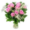 A soft yet striking bouquet of pink roses and baby's breath stands tall in a simple glass vase, photographed against a luminous white background that lets every gentle detail shine, like sunlight filtering into a Stanmore nursery. The arrangement centres on roughly ten to twelve pink roses, their blooms gathered into a full, rounded cluster. Each rose shows a slightly different moment in its life: some petals are still wrapped tightly around the core, forming compact, sculpted buds, while others open into generous, layered cups that reveal the intricate spirals inside. The colours range from delicate blush to a more confident, medium pink, with slightly deeper shades nestled at the centre of a few roses, adding character and depth. Woven among these focal blooms are airy sprigs of white baby's breath, the many tiny blossoms creating a feathery, cloud-like fill that suggests purity and the lightness of new beginnings. Framing the flowers are deep green leaves with a subtle gloss, their crisp outlines reinforcing the bouquet's shape and setting off the softer petals. The stems are gathered and visible through the clear glass vase, standing in clean water that reflects hints of green and acts as a simple, grounding base. Bright, even lighting illuminates the arrangement from above and around, showcasing the soft textures and dewy freshness without casting strong shadows. The mood is tender, hopeful, and calm, ideally suited to welcoming a newborn, celebrating a baby shower in a Stanmore home near Canons Drive, or offering a gentle, loving gesture to new parents. It feels both classic and fresh, like a timeless expression of joy for a new life.